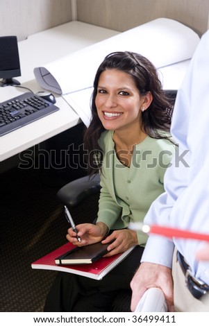 Hispanic female office worker sitting at cubicle desk