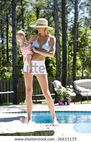 Mother carrying six month old baby next to a swimming pool
