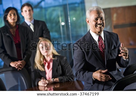 African American businessman in boardroom with colleagues standing behind him