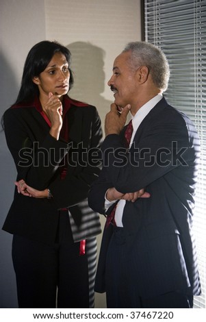 Multi-ethnic businesspeople having discreet conversation in corner of meeting room