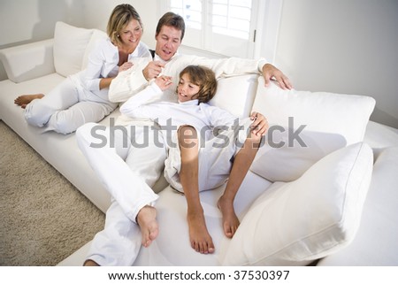 Parents and son relaxing on white sofa