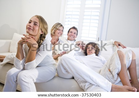Family sitting together on white sofa watching television