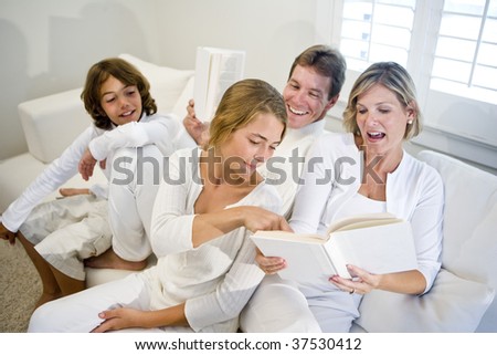 Family sitting on sofa together looking at book mom is reading