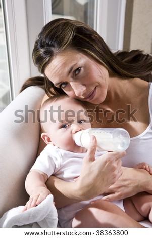 Mother feeding bottle to six month old baby