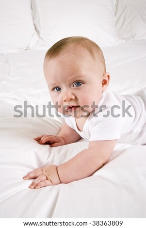 Cute six month old baby on a white bed