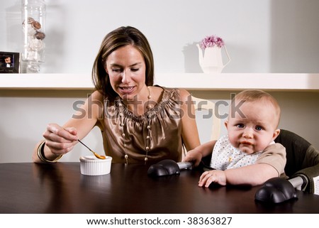 Mother feeding six month old baby sitting in high chair