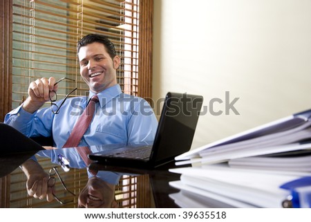 Happy male office worker sitting with laptop computer on table