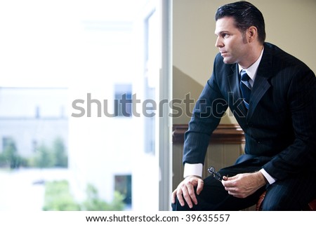 Serious businessman sitting in office looking out window