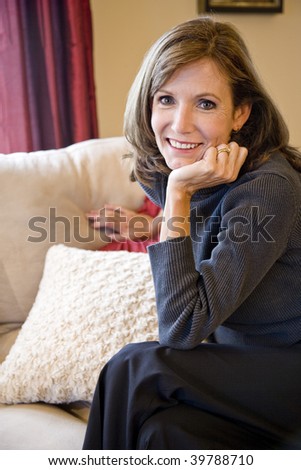 Attractive mature woman relaxing on couch in elegant modern living room