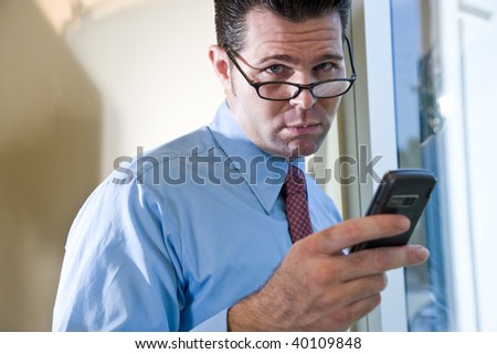 Serious male business executive sending text message on mobile phone