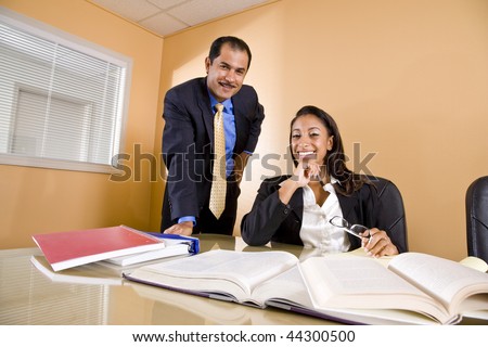 Young African-American female office worker with middle-aged Hispanic colleague in boardroom