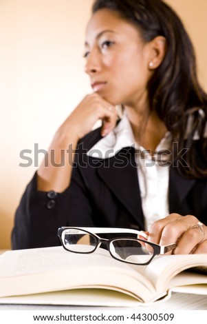 Serious young African-American woman thinking, focus on eyeglasses on book