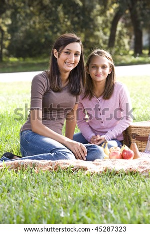 Sisters sitting on picnic blanket in park