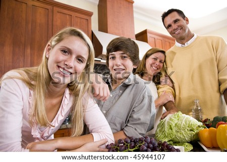Happy family with two teenagers standing together in kitchen