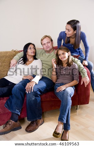 Interracial family sitting together at home on couch