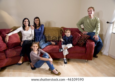 Portrait of interracial family of five sitting on living room sofa at home