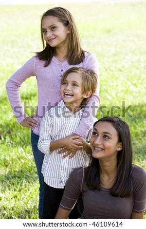 Cute 5 year old boy with two older sisters together outdoors on sunny day