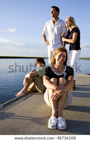 Mother enjoying sunny day on dock by water with family behind