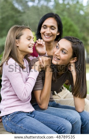 Affectionate Indian mother and two beautiful mixed-race daughters laughing together