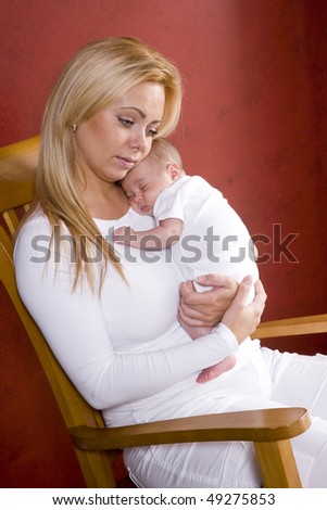 Happy young mother holding newborn baby in rocking chair