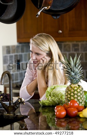 Pretty 17 year old teenage girl leaning on kitchen counter thinking