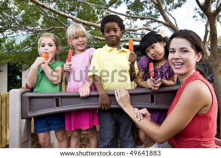 Diverse group of preschool 5 year old children playing in daycare with teacher