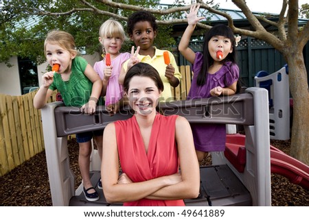 Diverse group of preschool 5 year old children playing in daycare with teacher