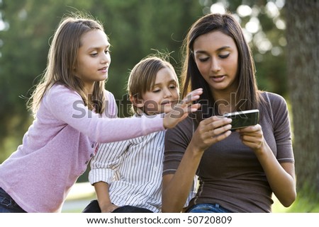 Teenage girl with mobile phone texting while younger siblings watch