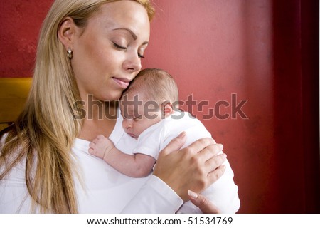 Contemplative young mother holding newborn baby in rocking chair