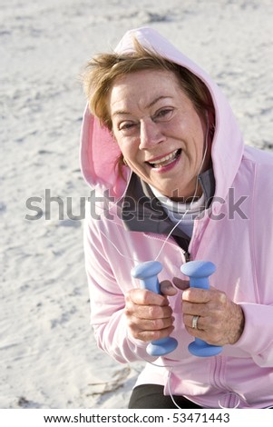 Senior woman exercising,  lifting hand weights on beach
