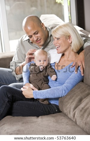 Loving parents with 3 month old baby sitting on lap at home