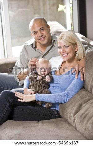 Loving parents with 3 month old baby sitting on lap at home