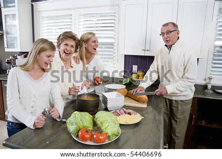 Three generation family in kitchen serving lunch, talking and laughing