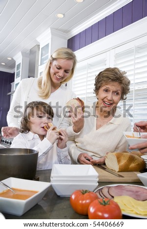 Three generation family in kitchen eating lunch, talking and laughing