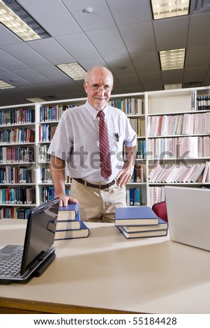 Portrait of mature man at library table with textbooks, professor researching