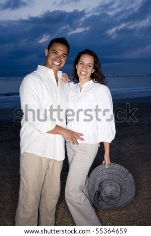 Happy mid-adult Hispanic couple smiling on beach at dawn