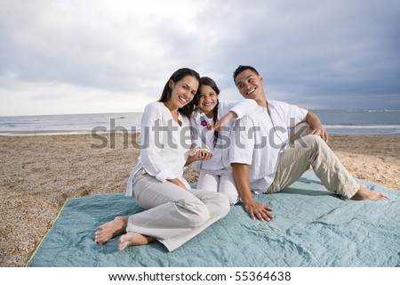 Latin American family with 9 year old girl sitting on blanket at beach