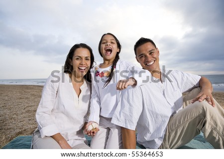 Latin American family with 9 year old girl sitting on blanket at beach