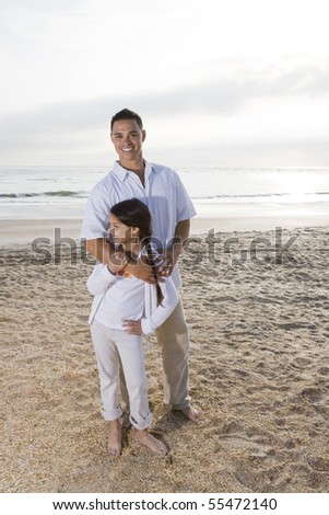 Hispanic father and 9 year old daughter standing together on beach