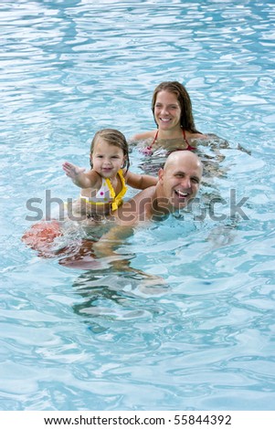 Family with 2 year old girl playing in swimming pool