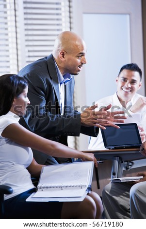 Hispanic business manager meeting with office workers, giving directions