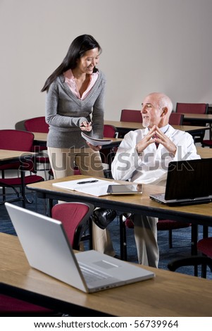 Doctor and female assistant in conference room looking at notebook