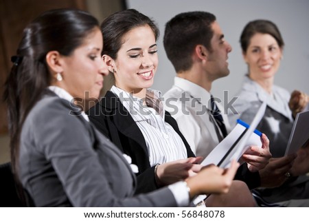 Young business people or college students sitting in row reading report in presentation