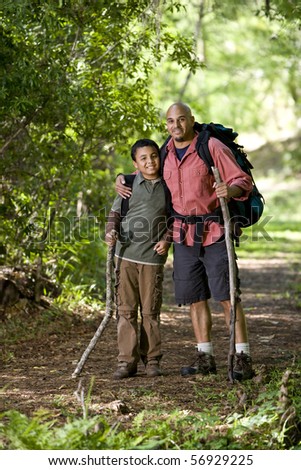 Father and 10 year old son hiking on trail in woods