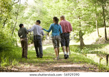 Rear view of Hispanic family walking along trail in park, boys 10 and 14 years old