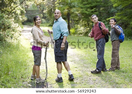 Hispanic family with two boys hiking in woods on trail