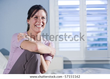 Happy mid-adult woman sitting on couch smiling