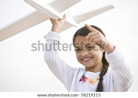 Smiling Hispanic girl playing with toy model plane