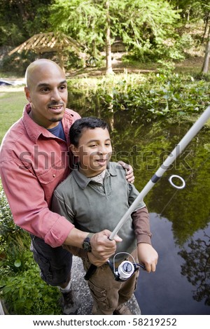 Hispanic father and 10 year old son fishing in pond