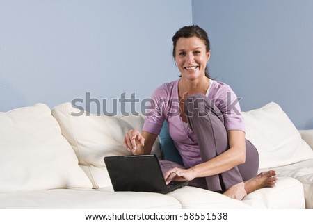 Portrait of mid-adult woman sitting on couch at home with laptop